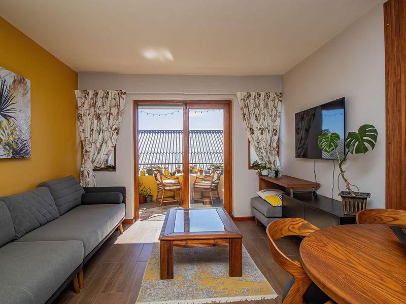 Open-plan living area featuring wood-look tile flooring, a vibrant accent wall, and sliding glass doors providing access to an outdoor balcony.