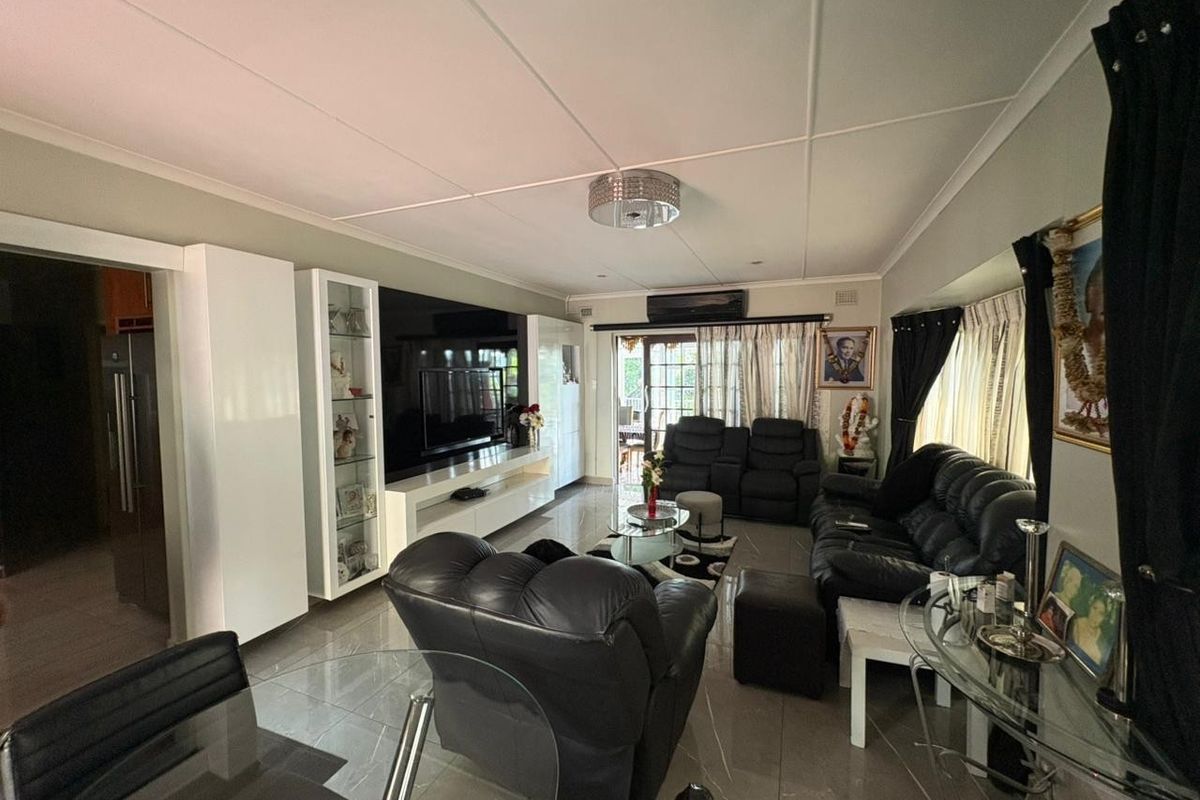 Spacious living room featuring tiled flooring, a built-in media wall unit, and a split-system air conditioner with direct access to the outdoor area.