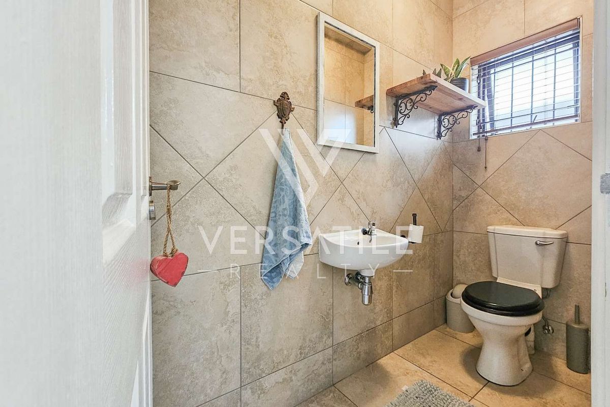 A compact guest bathroom featuring floor-to-ceiling wall tiles, a wall-mounted basin, and a standard toilet.