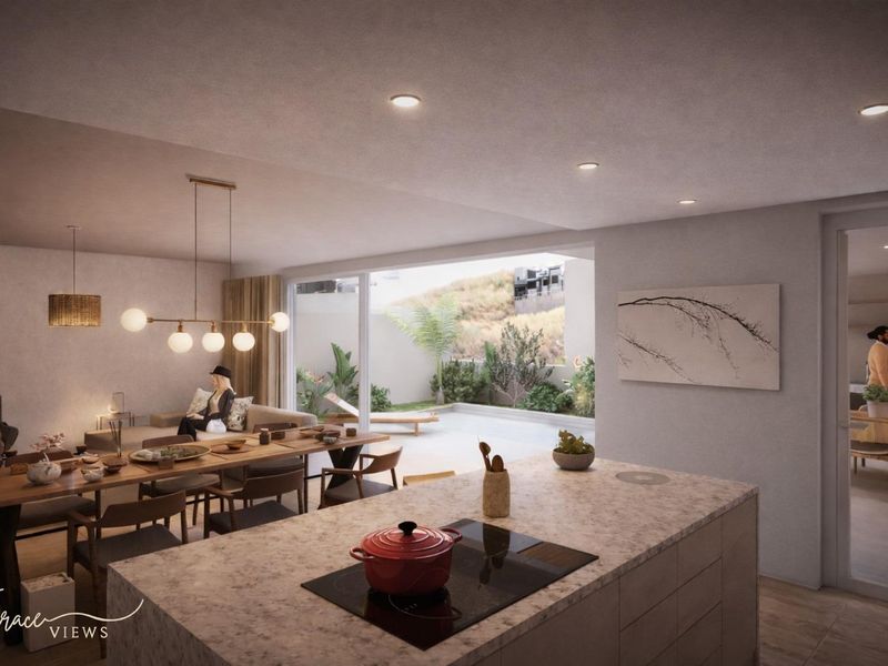 Modern open-plan living area featuring a kitchen island with stone countertops, induction cooktop, and seamless flow to an outdoor patio space.