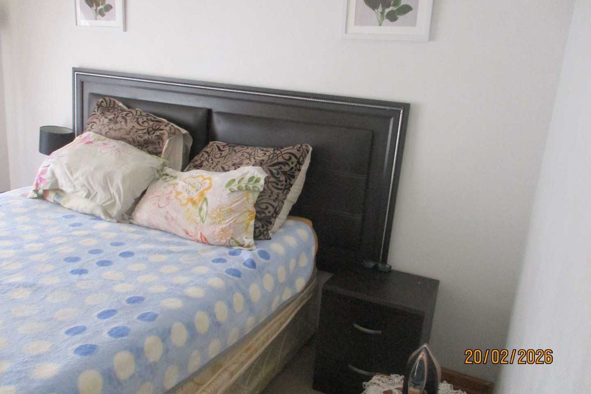 A bedroom featuring a built-in headboard and neutral wall finishes.
