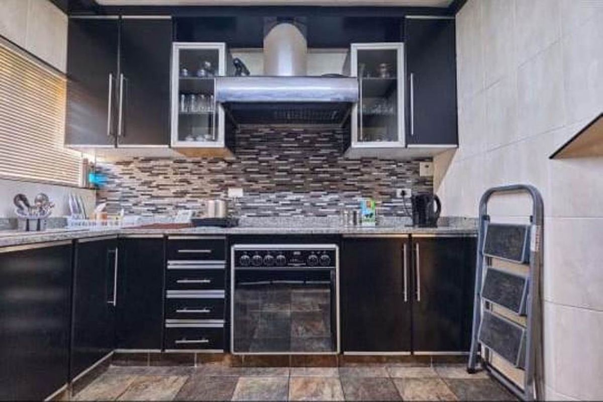 A functional kitchen featuring dark cabinetry, granite countertops, a mosaic tile backsplash, and a built-in oven with an extractor fan.