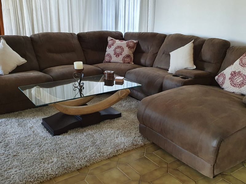 A comfortable living room area featuring tiled flooring and large windows with curtains, providing a bright and functional space for relaxation.