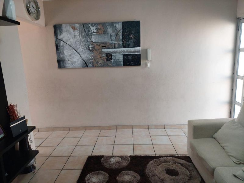 A living room area featuring neutral ceramic floor tiles and a wall-mounted intercom system.