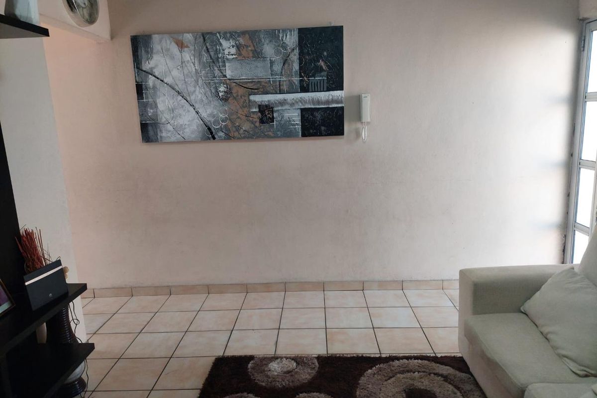 A living room area featuring neutral ceramic floor tiles and a wall-mounted intercom system.