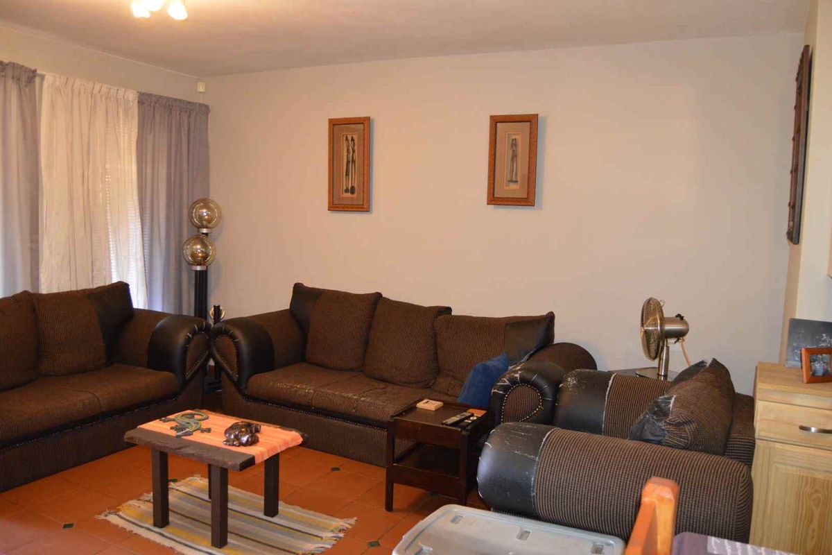 A living room featuring terracotta floor tiles and neutral wall finishes, providing a functional space for relaxation.