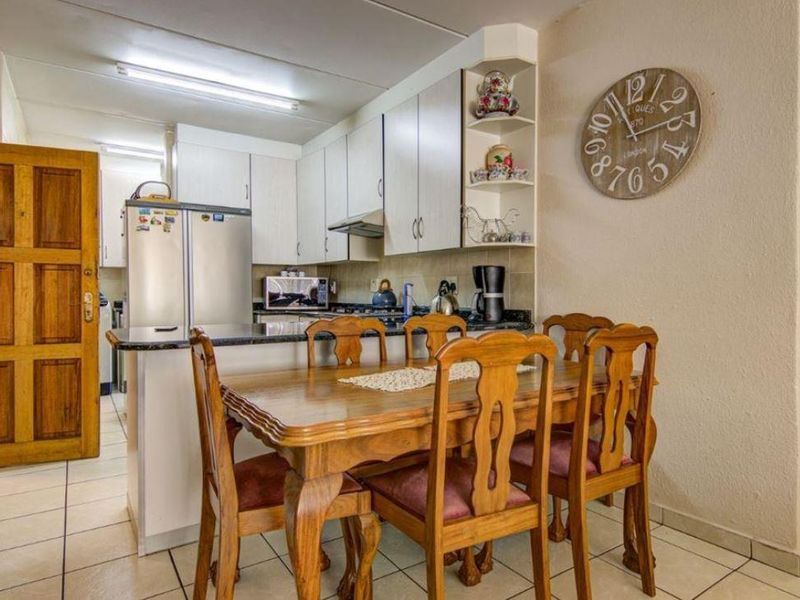 Open-plan kitchen and dining area featuring tiled flooring, built-in cabinetry with granite countertops, and an integrated extractor fan.