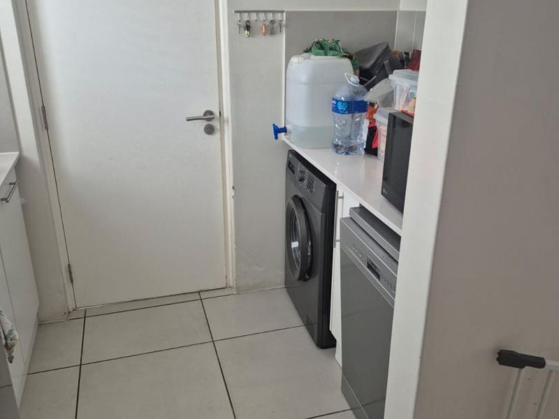 A functional laundry area featuring tiled flooring, built-in cabinetry, and dedicated space for appliances.
