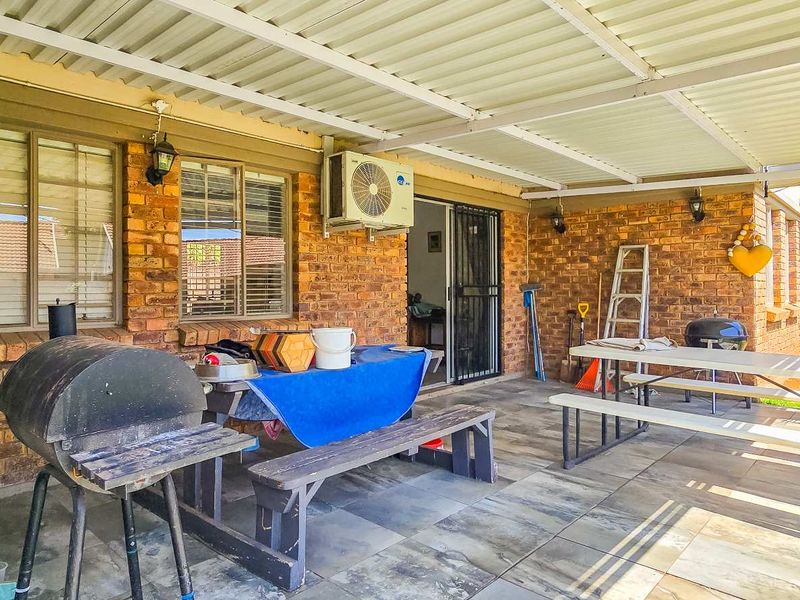 A covered outdoor patio area featuring brick walls, tiled flooring, and direct access to the interior via a sliding glass door.