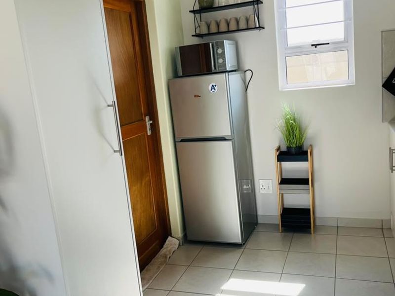 A functional kitchen area featuring tiled flooring, built-in cabinetry, and a window providing natural light.