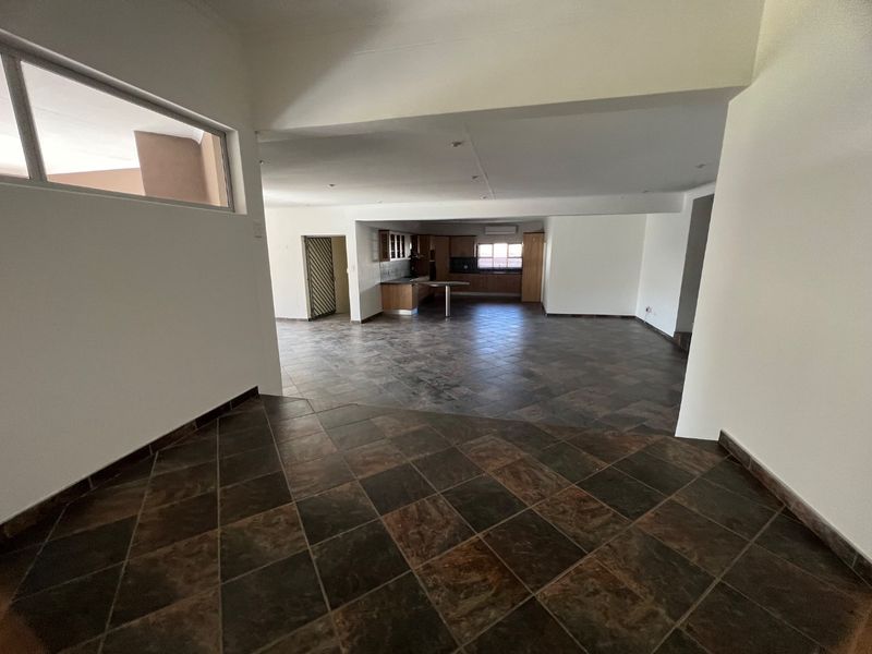Spacious open-plan living and kitchen area featuring dark tiled flooring, recessed lighting, and built-in cabinetry, offering a versatile layout for modern living.