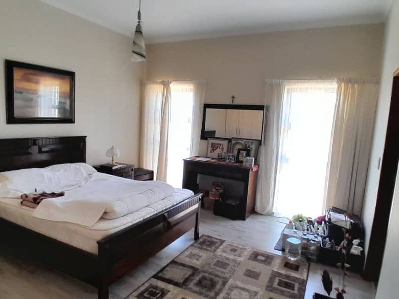 A spacious bedroom featuring light-toned laminate flooring and dual sliding glass doors that provide natural light.