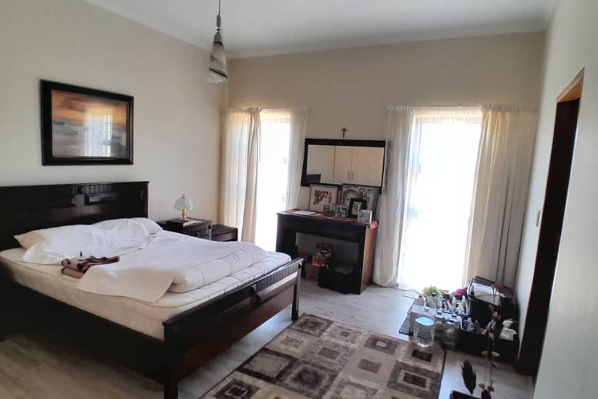 A spacious bedroom featuring light-toned laminate flooring and dual sliding glass doors that provide natural light.