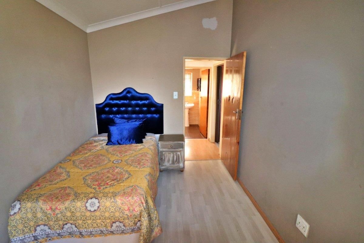 A bedroom featuring light-toned laminate flooring, neutral walls, and an adjoining en-suite bathroom.