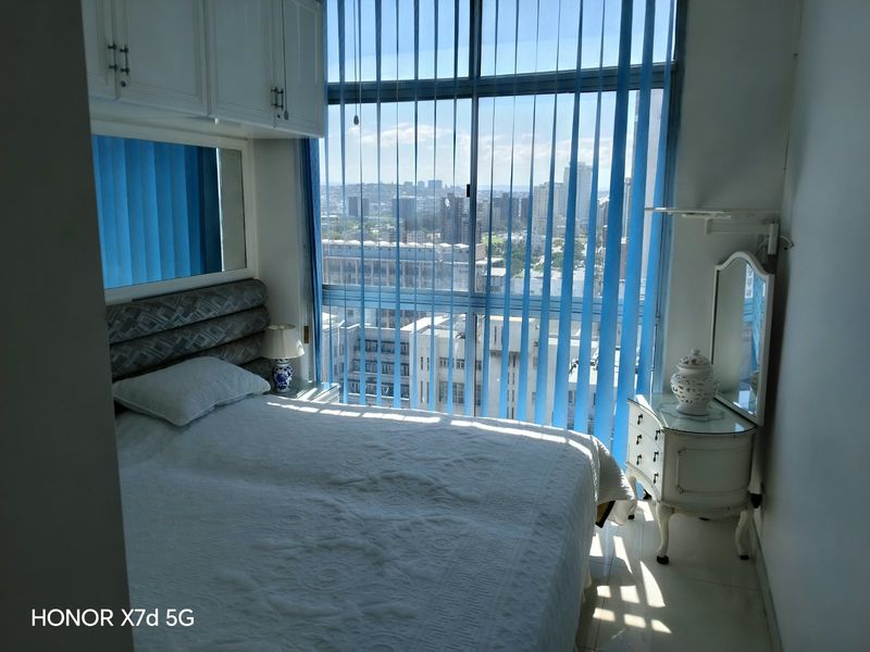 A bedroom featuring built-in cabinetry and large floor-to-ceiling windows offering an expansive city view.