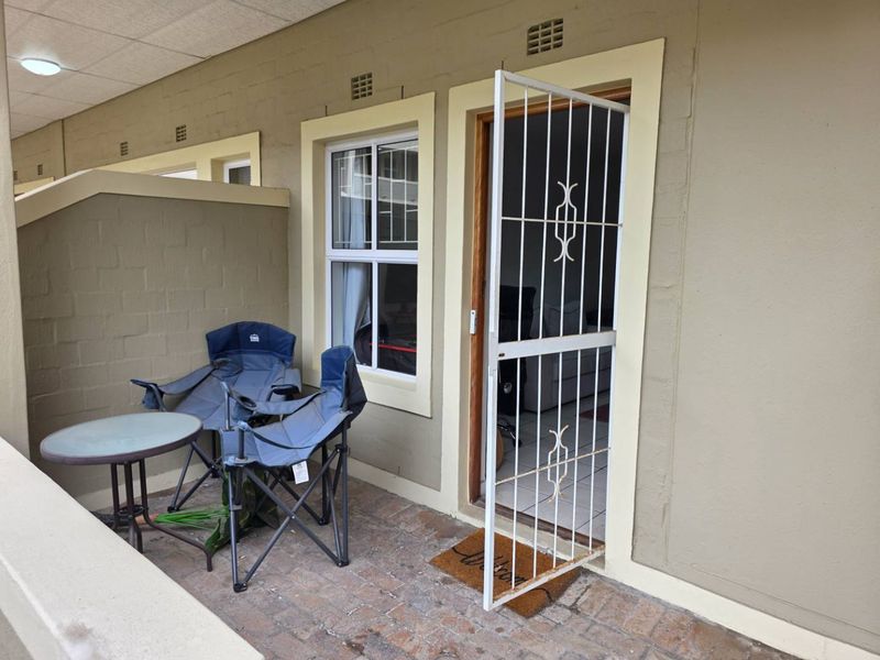 A covered patio area featuring brick paving, a security gate, and direct access to the interior living space.