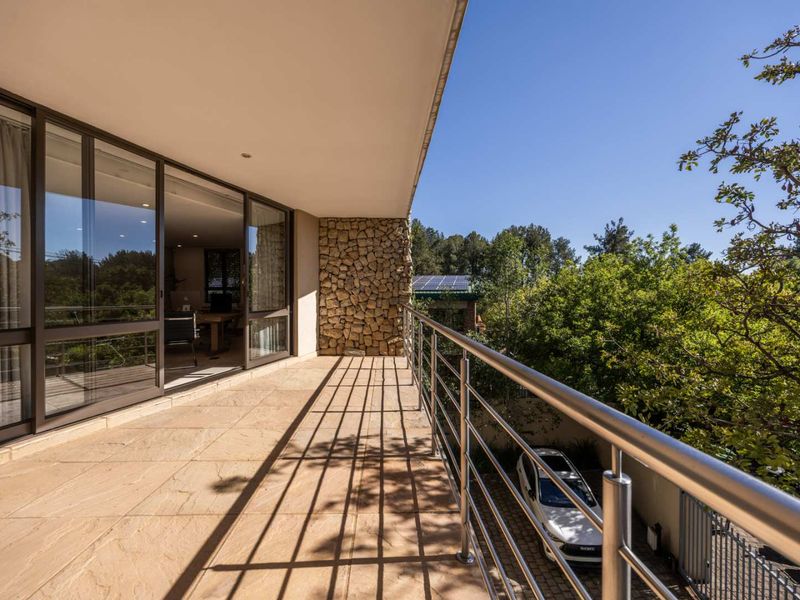 A spacious covered balcony featuring stone cladding, tiled flooring, and a stainless steel balustrade, offering a seamless transition to the interior office space.