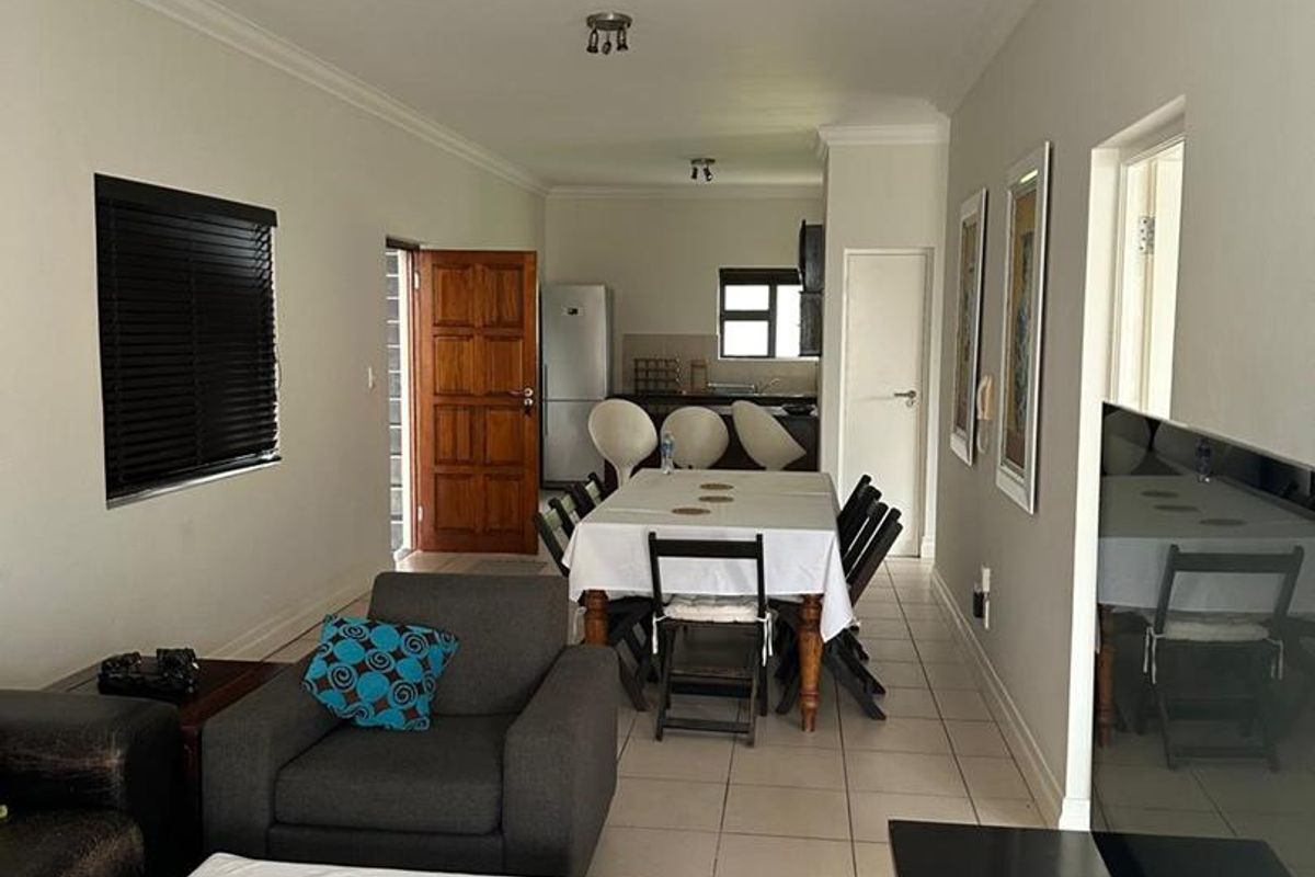 Open-plan living and dining area featuring neutral walls, tiled flooring, and direct access to the kitchen space.