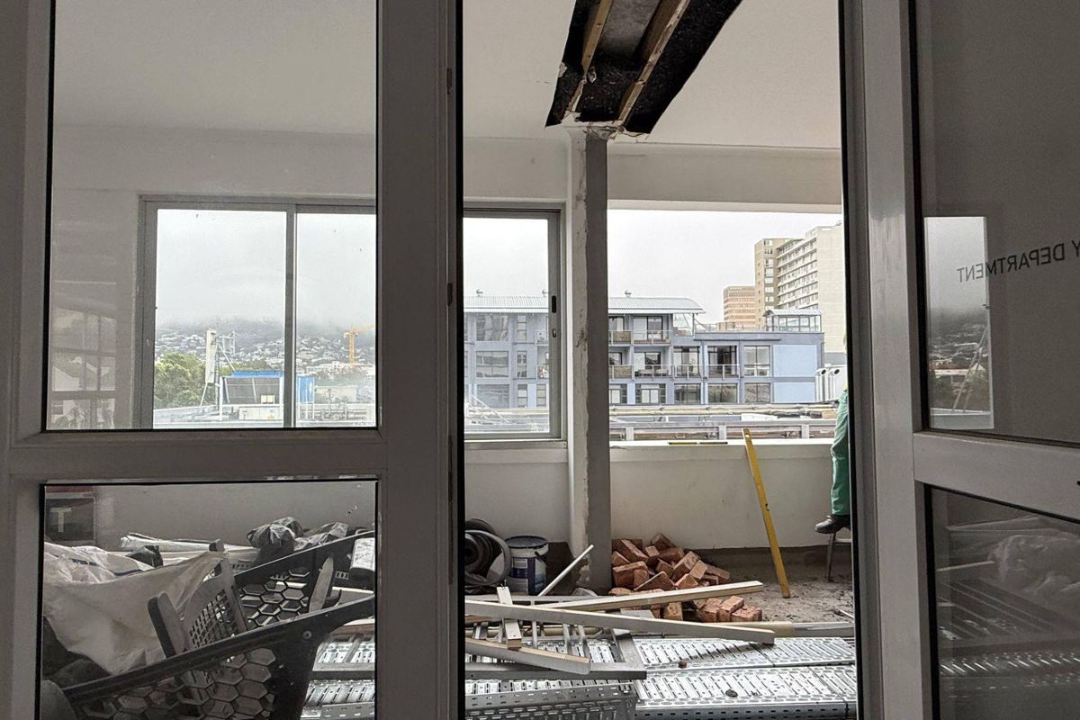 An unfinished balcony area currently under renovation, featuring exposed structural elements and sliding glass door access.