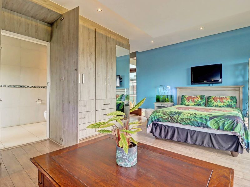 Spacious bedroom featuring built-in cupboards, recessed lighting, laminate flooring, and direct access to an en-suite bathroom.