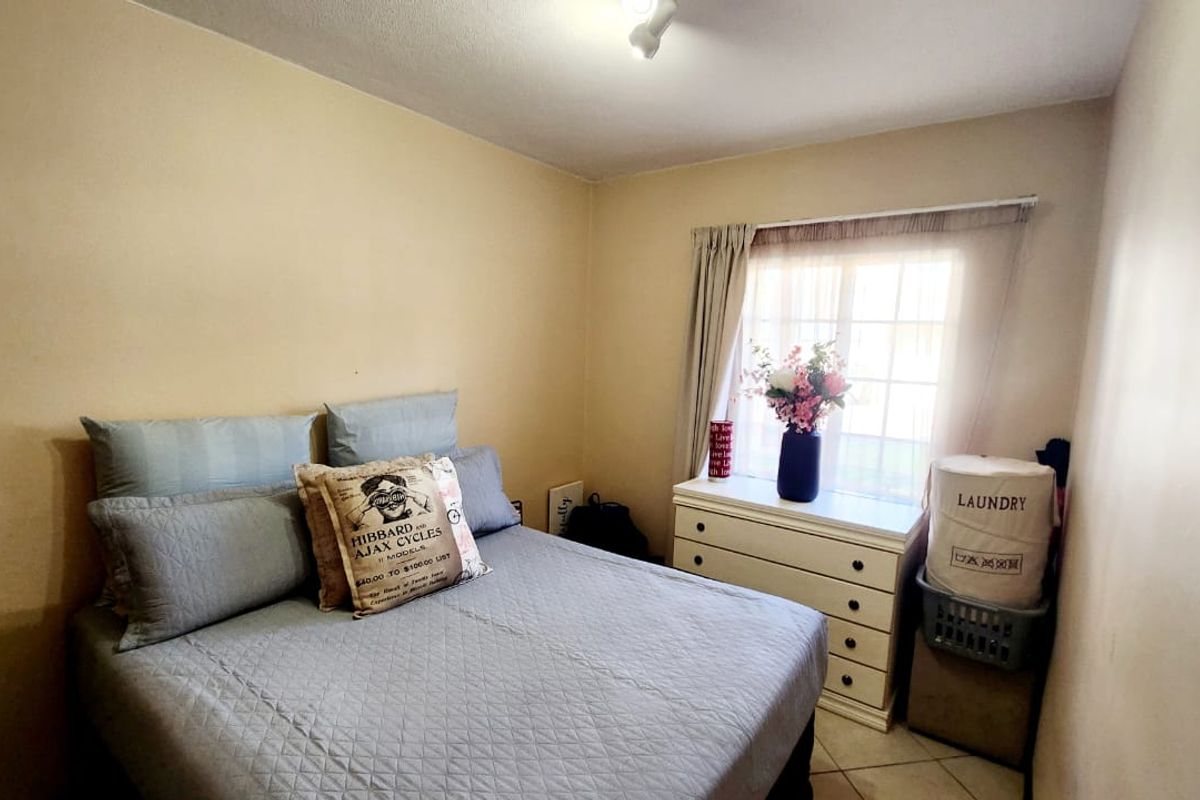 A standard bedroom featuring tiled flooring and a window with a curtain rail, providing a functional space for rest.