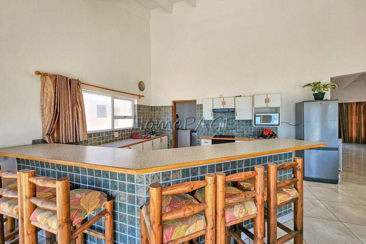 A functional kitchen featuring a breakfast bar, tiled countertops, and built-in cabinetry with high vaulted ceilings.