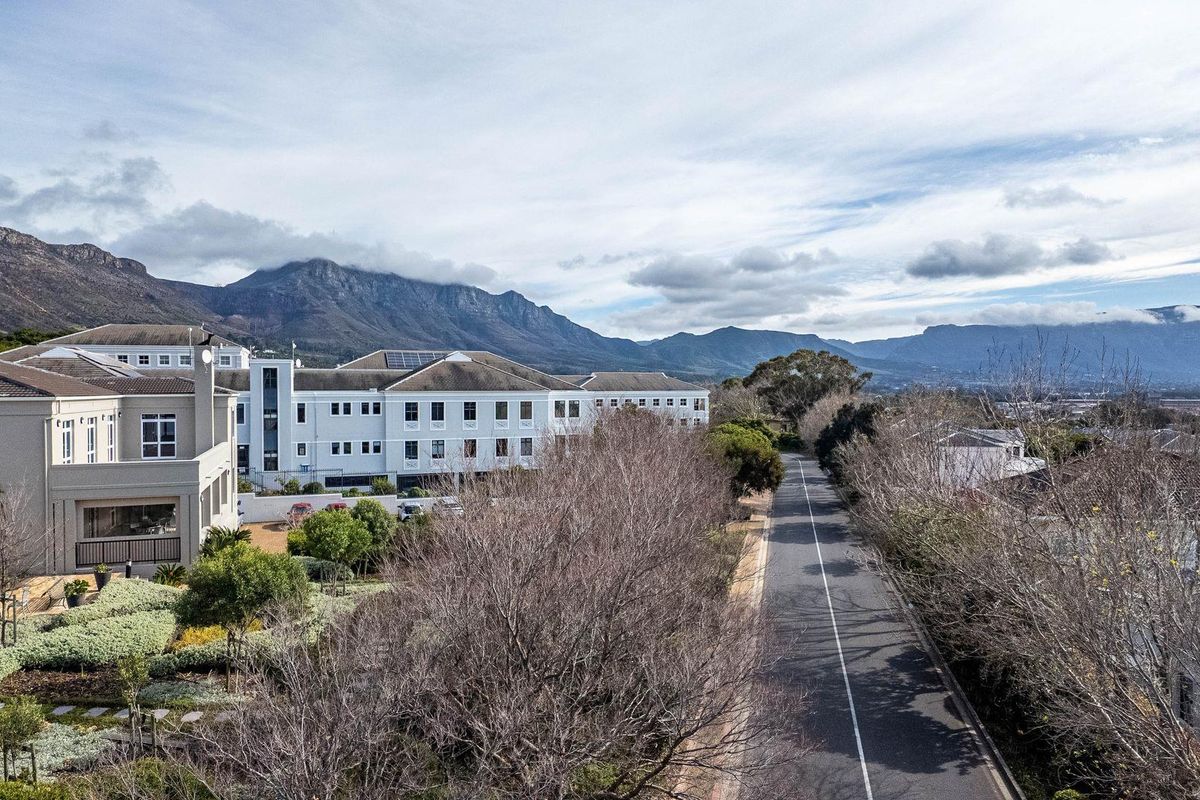 Aerial view of the office complex featuring landscaped gardens, paved pathways, and mountain views in a tranquil setting.