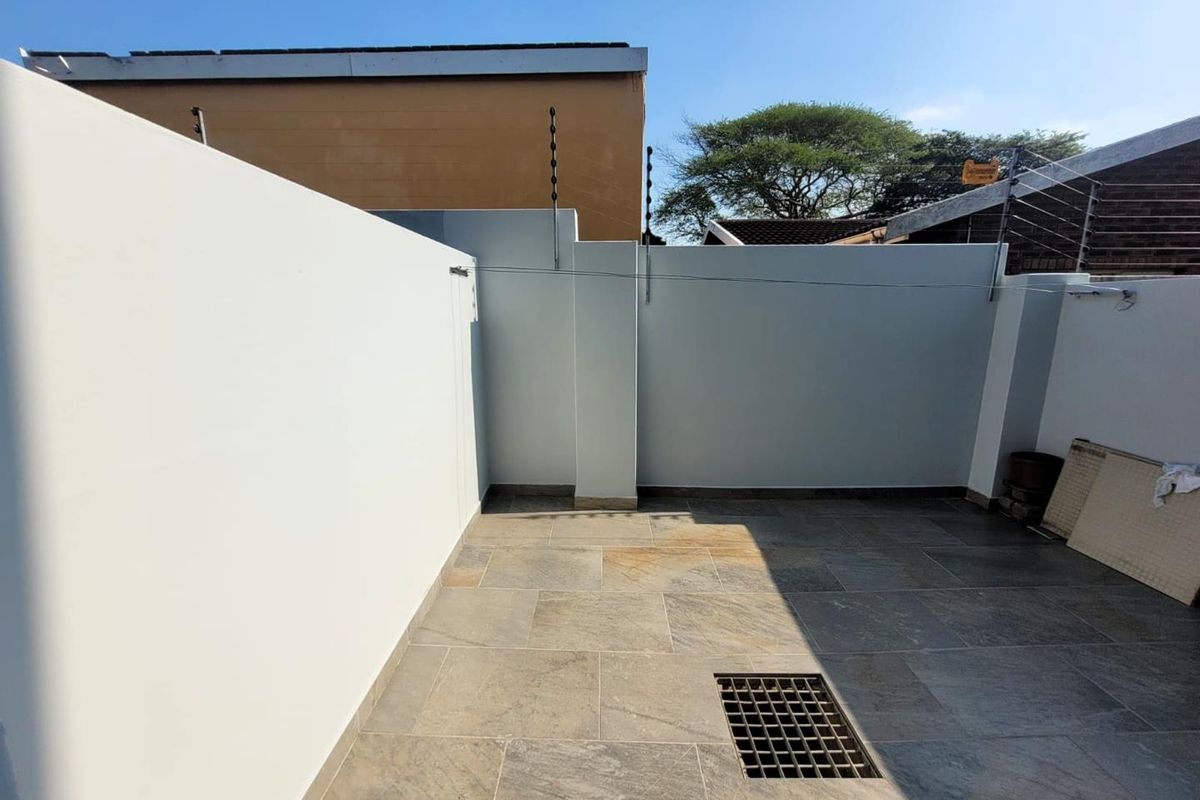 A private, paved outdoor courtyard area enclosed by high boundary walls with integrated electric fencing for added security.