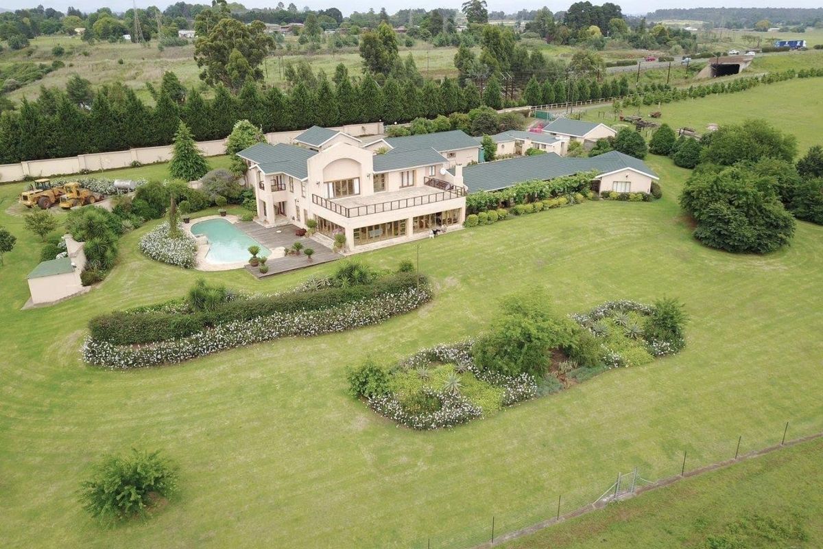 Aerial view of a large residential property featuring a spacious garden, swimming pool, and extensive landscaped grounds.