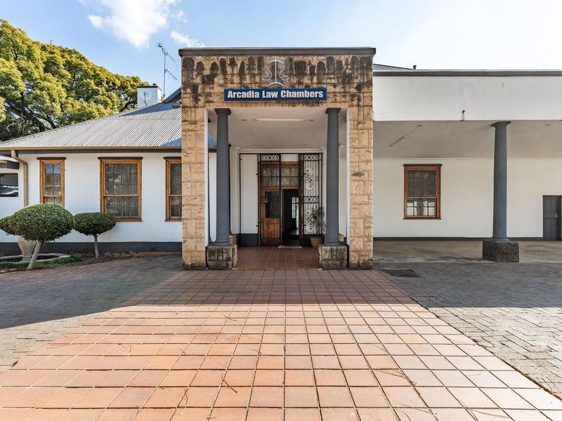 Front elevation of Arcadia Law Chambers featuring a stone-clad entrance, covered portico with columns, and paved driveway access.