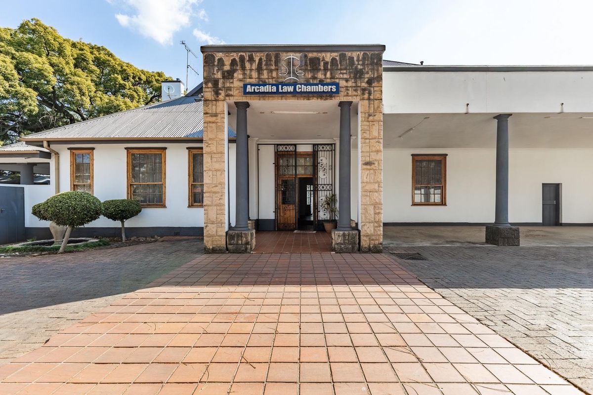Front elevation of Arcadia Law Chambers featuring a stone-clad entrance, covered portico with columns, and paved driveway access.