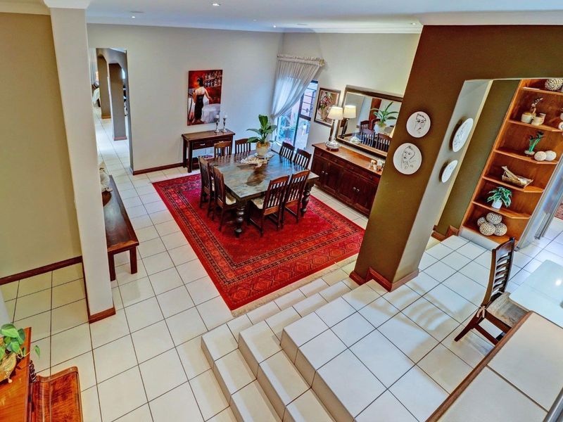 Spacious open-plan dining area featuring ceramic floor tiles, built-in shelving, and a stepped transition, creating a functional and well-defined living space.
