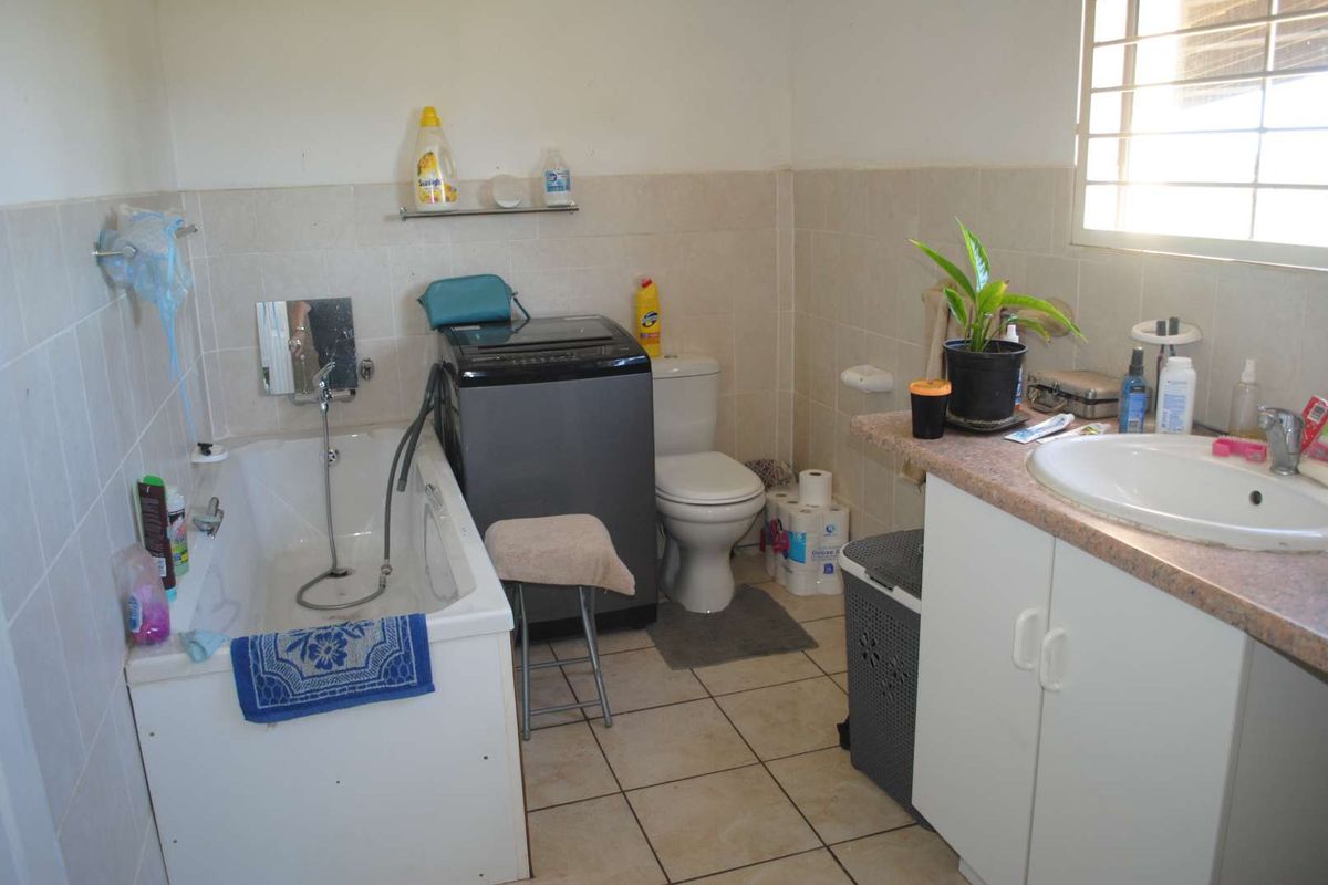 Functional bathroom featuring a bathtub, toilet, and vanity with a basin, finished with neutral wall and floor tiling.
