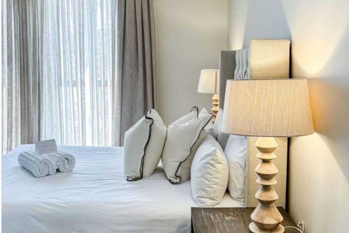 A well-maintained bedroom featuring neutral wall finishes, recessed ceiling lighting, and floor-to-ceiling window treatments.