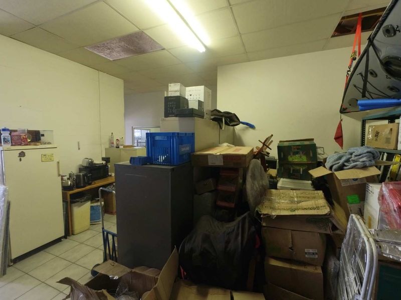 Utility storage area featuring tiled flooring and a suspended ceiling with integrated lighting, currently used for general storage.
