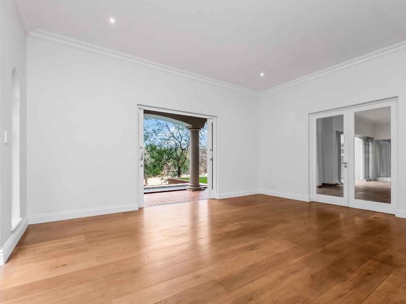 A bright, empty living room featuring hardwood flooring, crown molding, recessed lighting, and direct access to an outdoor patio area.