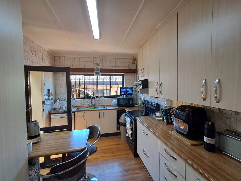 A functional kitchen featuring light-toned cabinetry, wood-look countertops, tiled backsplash, and integrated appliances, offering a practical layout for daily meal preparation.