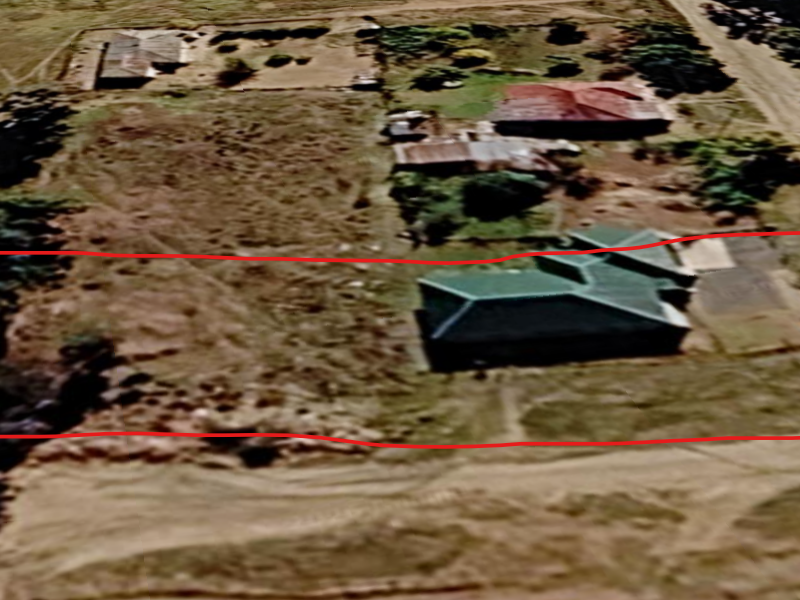 An aerial view of a residential vacant land plot featuring an existing dwelling and surrounding undeveloped grounds.