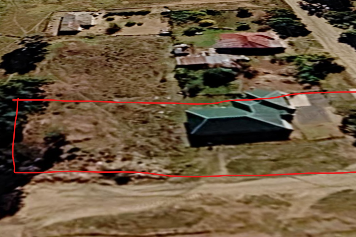 An aerial view of a residential vacant land plot featuring an existing dwelling and surrounding undeveloped grounds.