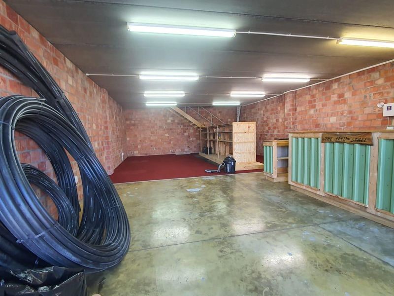 A spacious utility area featuring exposed brick walls, concrete flooring, and built-in service counters, suitable for storage, workshop, or commercial use.