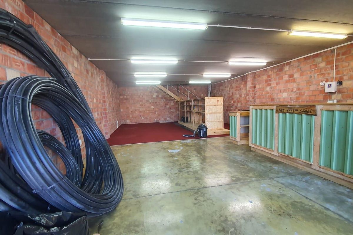 A spacious utility area featuring exposed brick walls, concrete flooring, and built-in service counters, suitable for storage, workshop, or commercial use.