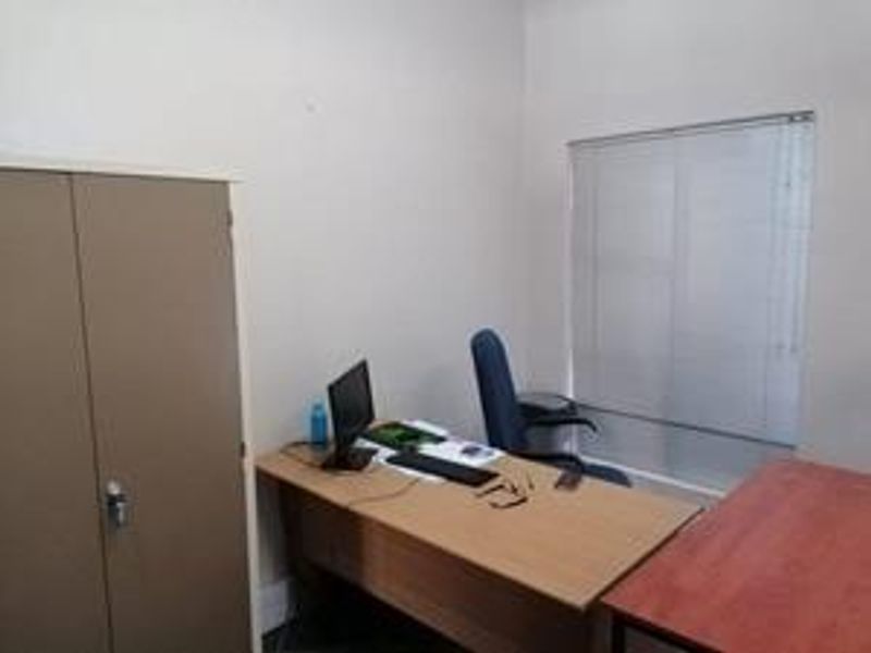 A functional office space featuring a built-in storage cupboard and window blinds, providing a practical work environment.