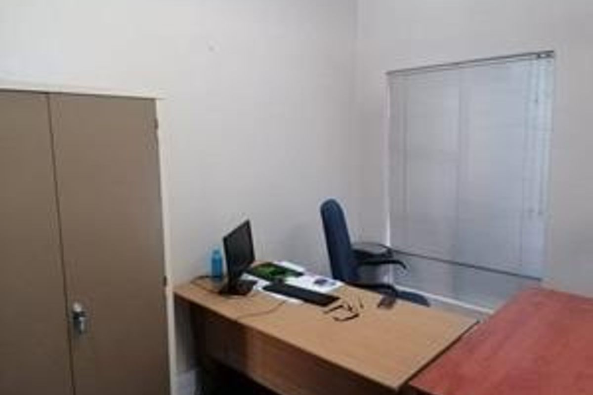 A functional office space featuring a built-in storage cupboard and window blinds, providing a practical work environment.