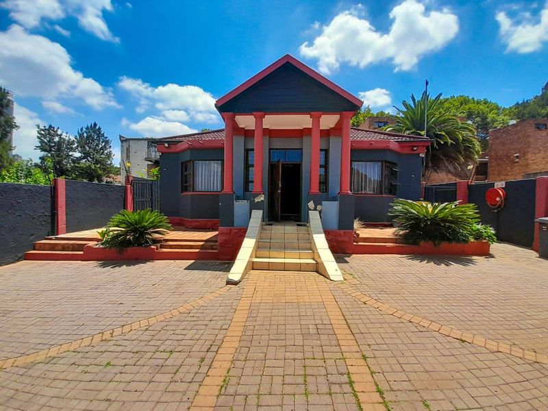 Front elevation of a house featuring a paved driveway, covered entrance porch with columns, and tiled steps leading to the main entrance.