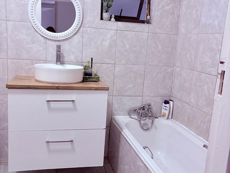 Modern bathroom featuring a wall-mounted vanity with a vessel sink, tiled walls, and a built-in bathtub.