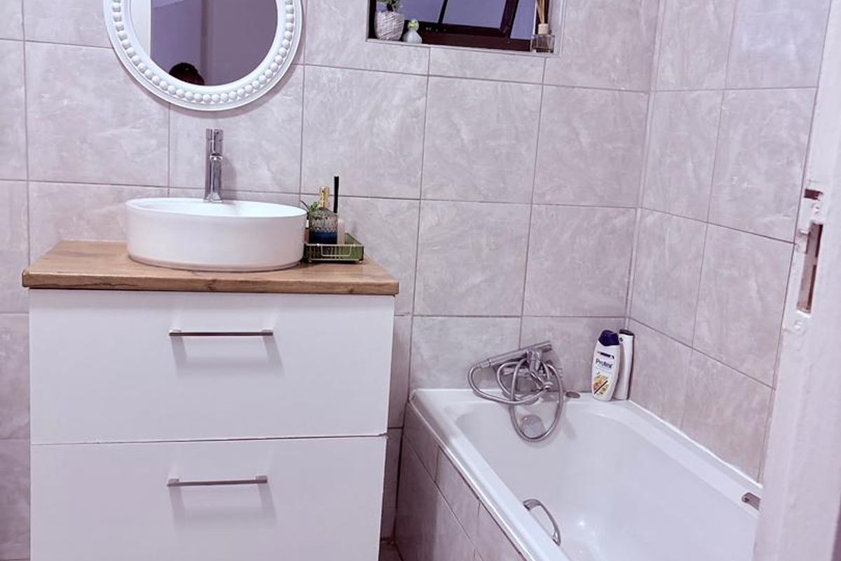 Modern bathroom featuring a wall-mounted vanity with a vessel sink, tiled walls, and a built-in bathtub.