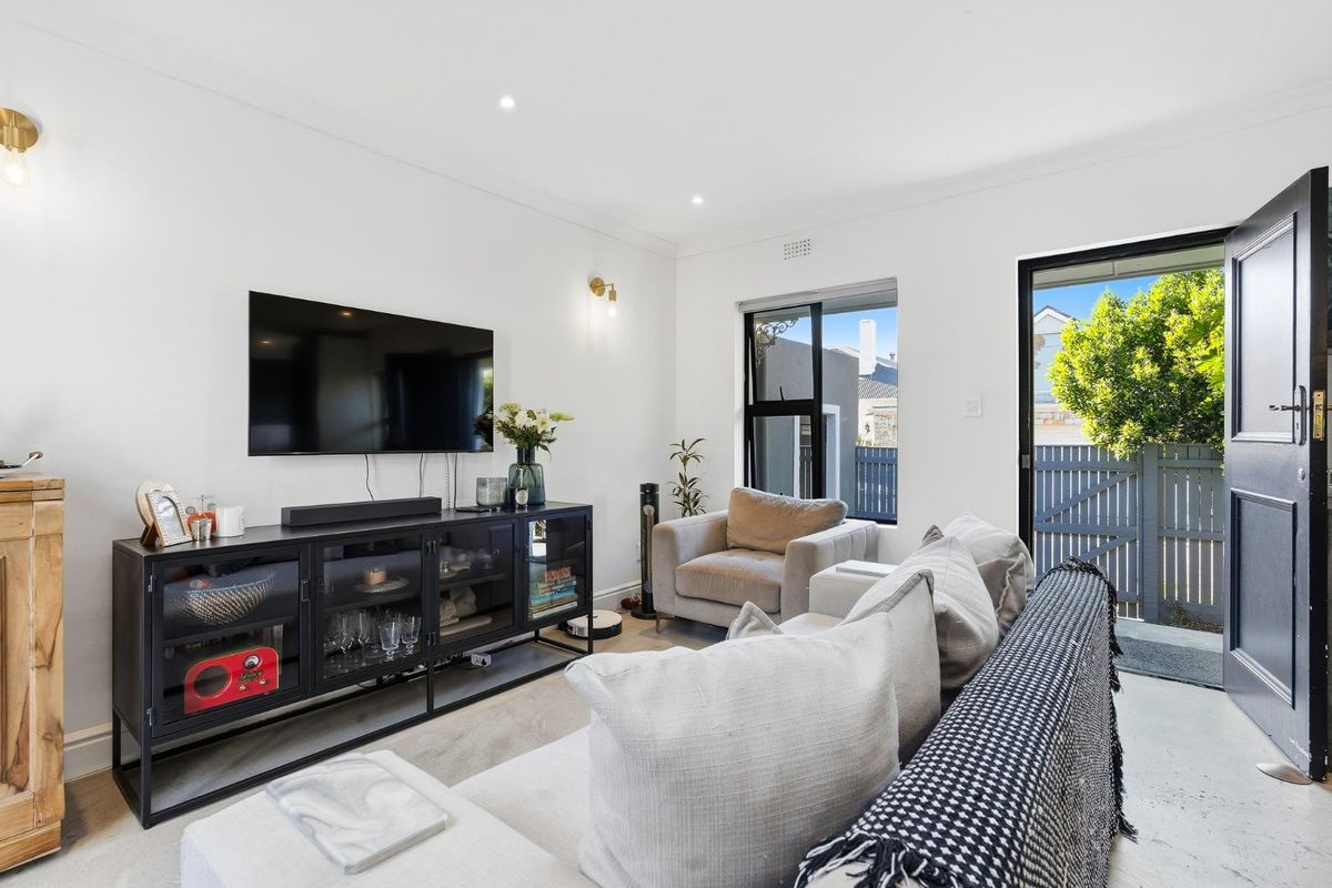 A bright and modern living room featuring recessed downlights, neutral finishes, and direct access to an outdoor area through a sliding glass door.