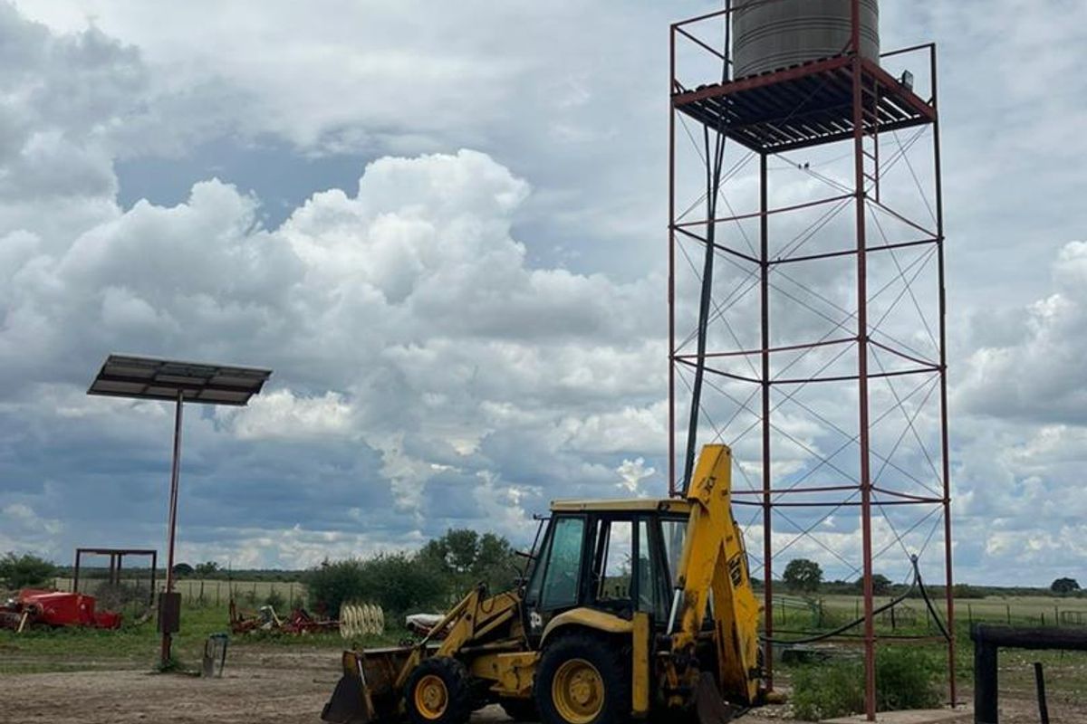 Farm yard area featuring an elevated water storage tank on a steel structure and a solar panel installation.