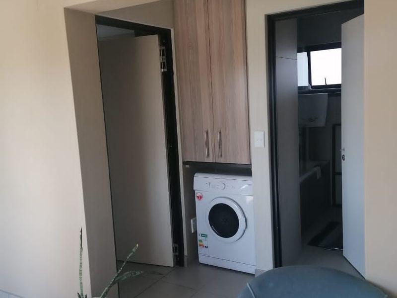 A functional laundry nook featuring built-in cabinetry and tiled flooring, conveniently positioned between internal doorways.