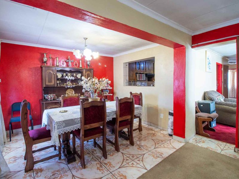 Open plan dining area featuring tiled flooring and a pass-through window connecting to the kitchen, with bold red accent walls.